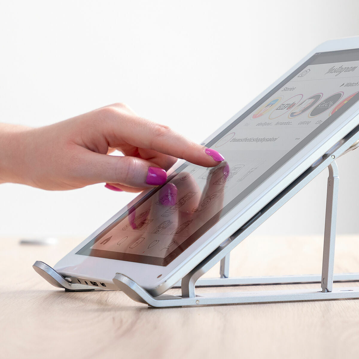Folding adjustable laptop stand raising a laptop on a kitchen table