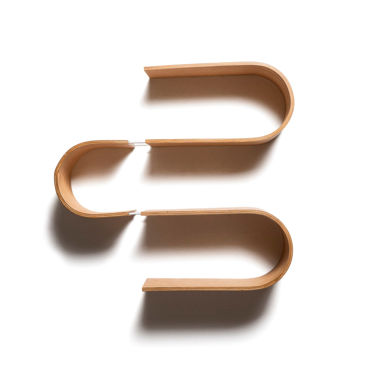 Empty Snake S-shaped wooden wall shelf on a white wall