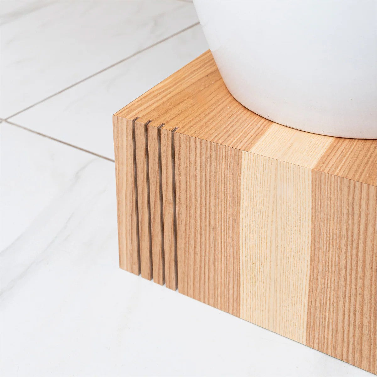 Close-up of a wooden cube plant stand under a white pot