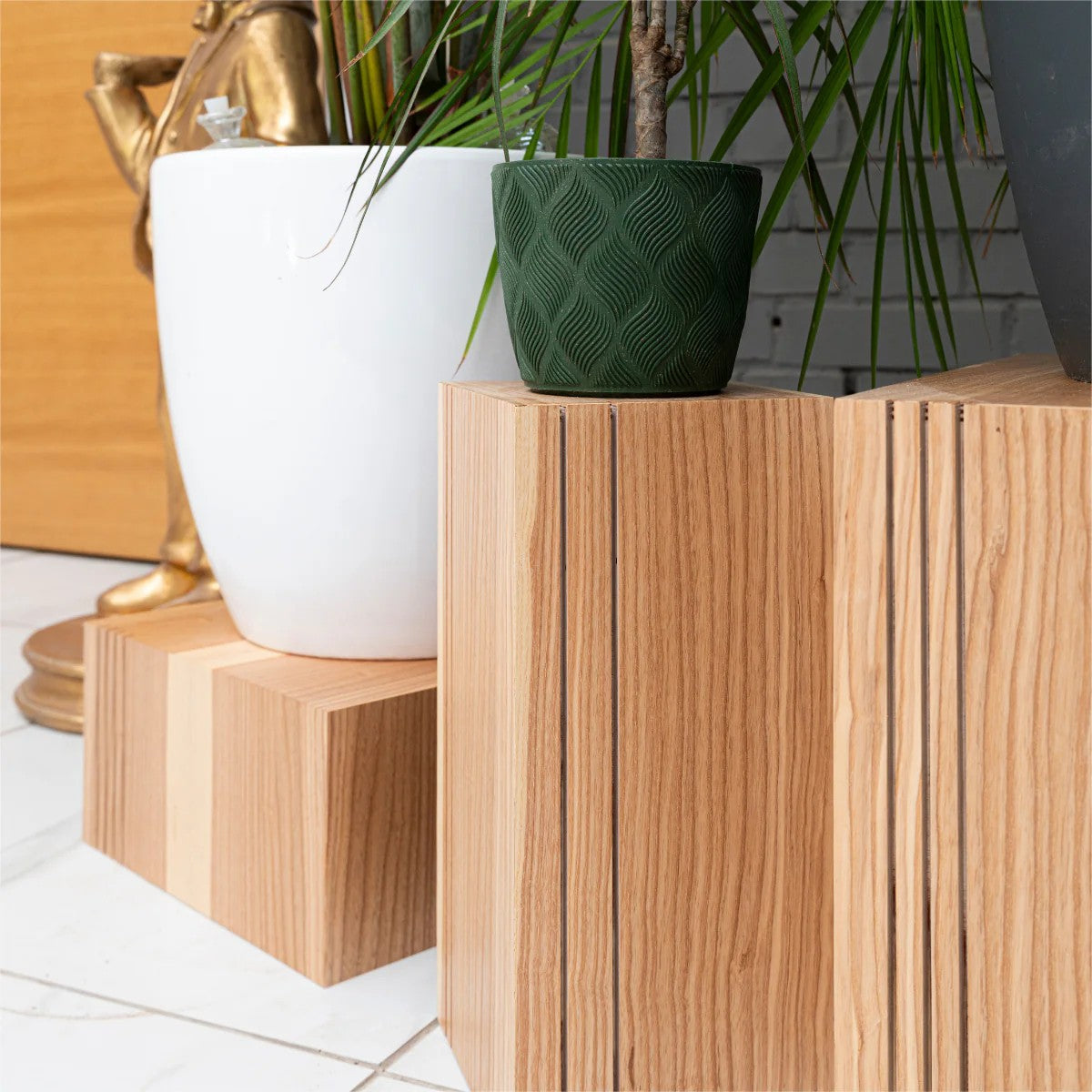 Tall and low wooden cube plant stands holding white and green pots